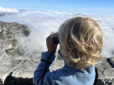 Junge schaut mit Fernglas über die Landschaft vom Tafelberg – Südafrika mit Kindern