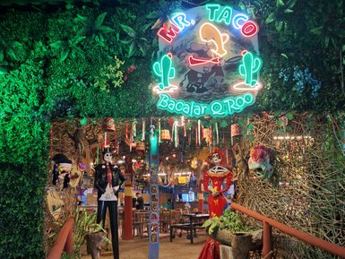 Der Eingang zu Mr. Taco in Bacalar ist lebhaft dekoriert mit bunten Lichtern und Pflanzen, die eine einladende Atmosphäre schaffen.