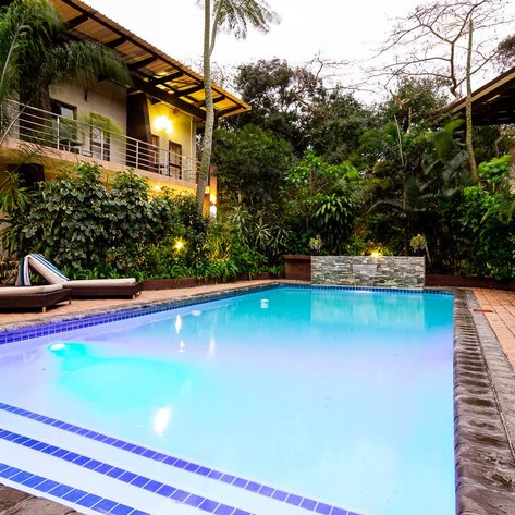 Ein einladender Pool umgeben von üppigem Grün und modernen Liegen, ideal für Entspannung in der Natur.