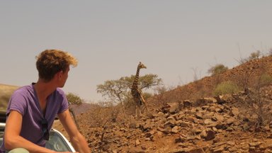 Ein Junge beobachtet gespannt eine Giraffe - Namibia mit Jugendlichen