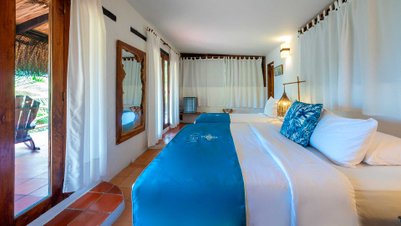 Ein helles Hotelzimmer mit zwei Betten, dekoriert mit blauen Überwürfen und einem bunten Kissen, strahlt Gemütlichkeit aus.