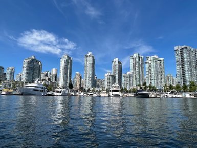 Die Skyline von Vancouver spiegelt sich im ruhigen Wasser, umgeben von modernen Wolkenkratzern und Yachten im Hafen.