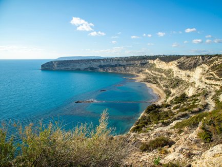 Eine atemberaubende Küstenlandschaft mit klarem, blauem Wasser und sanften Hügeln, die sich entlang der Küste erstrecken.