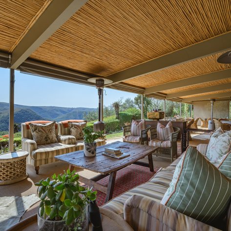 Ein einladender Außenbereich mit gemütlichen Sofas und einem Holztisch, umgeben von einer malerischen Landschaft.