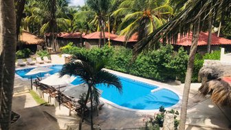 Ein einladender Pool umgeben von Palmen und Sonnenliegen, ideal für Entspannung in der tropischen Sonne.