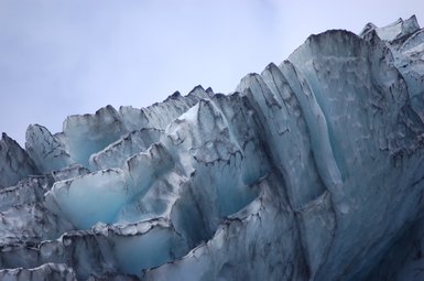Die beeindruckenden Eiskanten des Gletschers erheben sich majestätisch gegen den klaren Himmel und zeigen ihre bläuliche Farbe.