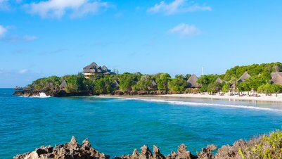 Ein malerischer Blick auf die Küste von Chale Island mit sanften Wellen und üppiger Vegetation im Hintergrund.