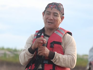 Ein Mann in einem roten Schwimmwesten spricht mit Begeisterung auf einem Boot am Amazonas in Peru.