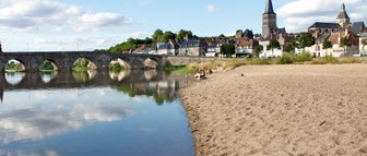 Ein ruhiger Strandabschnitt mit feinem Sand, der sanft ins Wasser übergeht, während Wolken sich im klaren Wasser spiegeln.