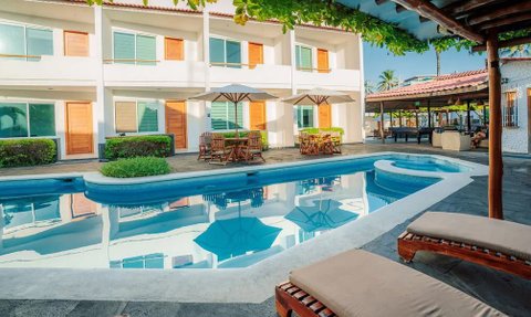 Ein einladender Poolbereich mit Liegen, Sonnenschirmen und einem Blick auf die modernen Hotelzimmer im Hintergrund.