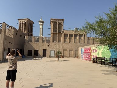 Ein Junge steht in einem historischen Stadtviertel von Dubai und fotografiert die beeindruckenden Windtürme im Hintergrund.