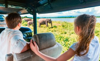 Eine Familie fährt im offenen Jeep durch den Udawalawe Nationalpark auf der Suche nach wilden Tieren – Sri Lanka mit Kindern