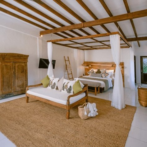 Ein helles, modernes Familienzimmer mit zwei Betten, Holzdetails und einem gemütlichen Teppich auf dem Boden.