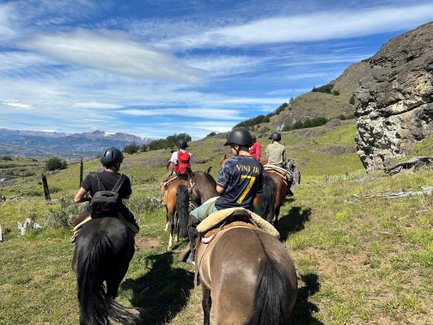 Eine Gruppe von Reitern auf Pferden erkundet die malerische Landschaft Patagoniens unter einem strahlend blauen Himmel.