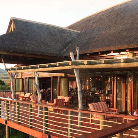 Ein stilvolles Restaurant mit einem Strohdach, umgeben von einer malerischen Landschaft und einer einladenden Terrasse.