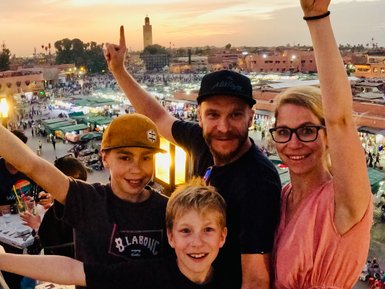 Familie hält einen Moment mit einem Selfie auf dem abendlich Djemaa el Fna in Marrakesch fest – Marokko mit Kindern