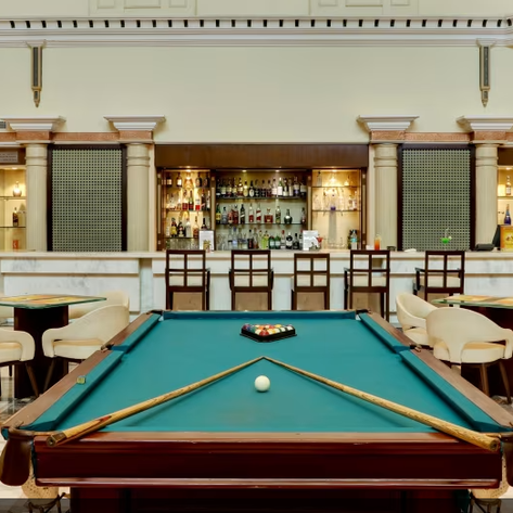 Ein eleganter Billardtisch mit einem weißen Ball und einem Set von bunten Kugeln in einem stilvollen Barbereich.