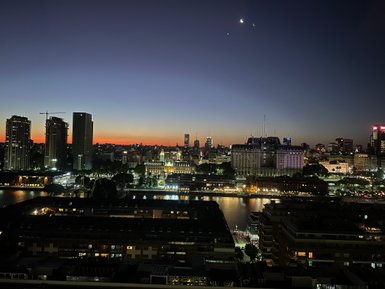 Die Skyline von Buenos Aires erstrahlt im Dämmerlicht, während der Fluss sanft im Hintergrund glitzert.