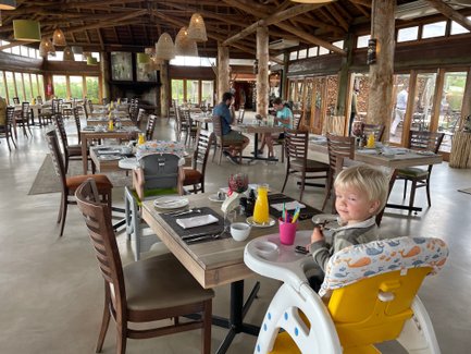 Fröhliches Kind sitzt im Restaurant der Garden Route Game Lodge und lächelt – Garden Route Familienreise
