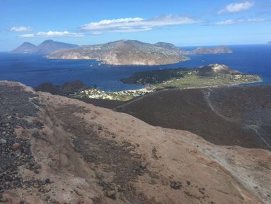 Ein atemberaubender Blick vom Krater auf die Küste mit klarem blauen Wasser und grünen Hügeln im Hintergrund.