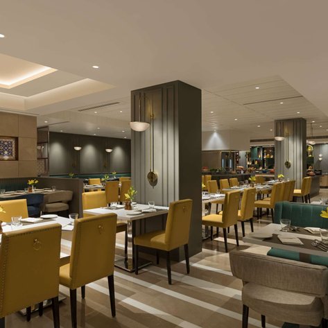 Ein elegantes Restaurant mit modernen Möbeln, gelben Stühlen und Tischen, die mit frischen Blumen dekoriert sind.