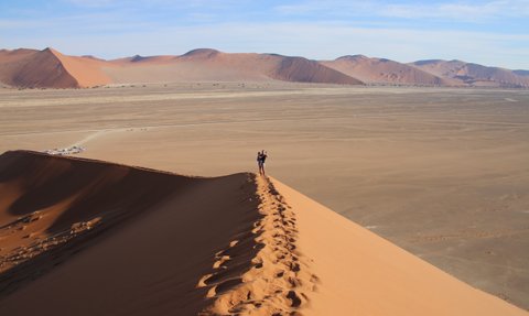 Eine Mutter steht mit ihrem Kind auf dem Arm auf einer Düne - Namibia Reise mit Kindern
