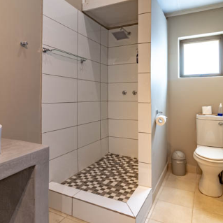 Ein modernes Badezimmer mit einer eleganten Dusche, einem Waschbecken und einem Fenster, das natürliches Licht hereinlässt.