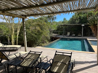 Ein entspannender Poolbereich im Kariega Game Reserve, umgeben von üppigem Grün und Sonnenliegen auf einer Holzterrasse.