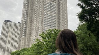 Eine Person mit einem Rucksack steht im Vordergrund, während sie die beeindruckenden Hochhäuser von Tokio betrachtet.