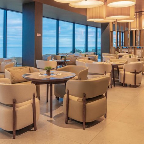 Ein eleganter Essbereich mit modernen Möbeln und großen Fenstern, die einen Blick auf das Meer bieten.