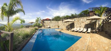 Ein einladender Poolbereich mit Liegen und Sonnenschirmen, umgeben von üppigem Grün und einer beeindruckenden Aussicht.