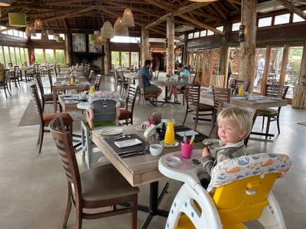 Fröhliches Kind sitzt im Restaurant der Garden Route Game Lodge und lächelt – Garden Route Familienreise