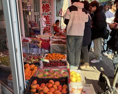 Ein belebter Markt in Peking, wo Menschen frisches Obst aus bunten Körben auswählen und kaufen.