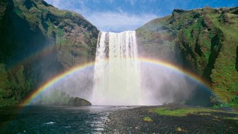 Ein majestätischer Wasserfall stürzt in einen klaren Fluss, während ein strahlender Regenbogen die Szenerie überquert.