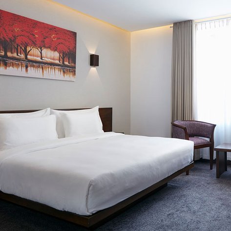 Ein modernes Hotelzimmer mit einem großen Bett, eleganten Stühlen und einem Tisch, der mit Getränken dekoriert ist.