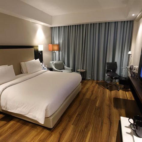 Ein modernes Hotelzimmer mit einem großen Bett, eleganten Möbeln und einem Fernseher an der Wand, ideal für Entspannung.