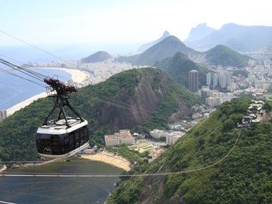 Eine Seilbahn schwebt über der Küste von Rio de Janeiro, mit Aussicht auf den Strand und die umgebenden Berge.