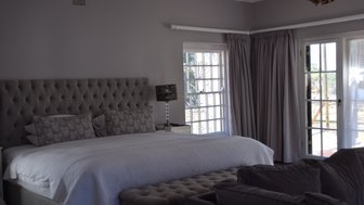 Ein elegantes Schlafzimmer mit einem großen, gepolsterten Bett und stilvollen Kissen, das Gemütlichkeit ausstrahlt.