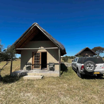 Eine gemütliche Unterkunft in der Natur, umgeben von Graslandschaft und einem strahlend blauen Himmel.