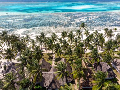 Eine atemberaubende Aussicht auf Karafuu Beach Resort, umgeben von Palmen und dem glitzernden blauen Wasser des Indischen Ozeans.