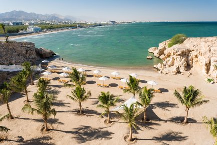 Strand des Crowne Plaza Muscat mit Liegestühlen und Sonnenschirmen – Familienurlaub in Muscat
