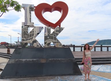 Mädchen steht stolz neben dem bekannten Kota Kinabalu Schriftzug – Malaysia & Borneo Reise mit Kindern