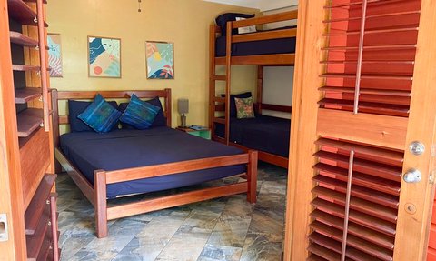 Ein gemütliches Zimmer mit einem Doppelbett und einem Etagenbett, umgeben von warmen Farben und Holzdetails.