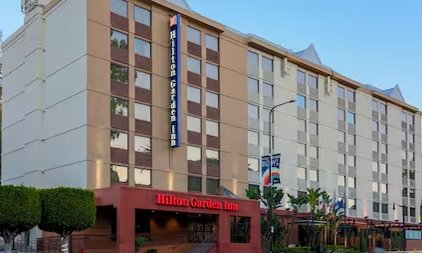 Das Hilton Garden Inn ist ein modernes, mehrstöckiges Gebäude mit einer einladenden Fassade und einem klaren Himmel im Hintergrund.