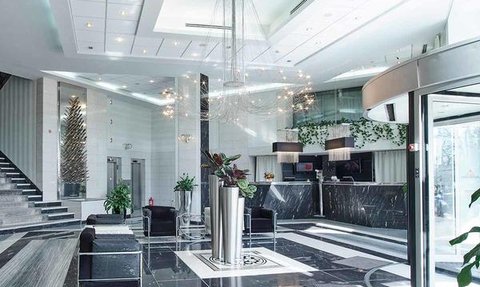 Der elegante Empfangsbereich des Continental Forum Sibiu Hotels zeigt moderne Möbel und eine stilvolle Treppe im Hintergrund.