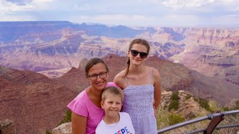 Eine Familie posiert am Grand Canyon, umgeben von beeindruckenden Felsformationen und einer weiten Landschaft.