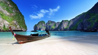 Küstenabschnitt mit Felsformationen und traditionellem Boot – Thailand Reise mit Kindern