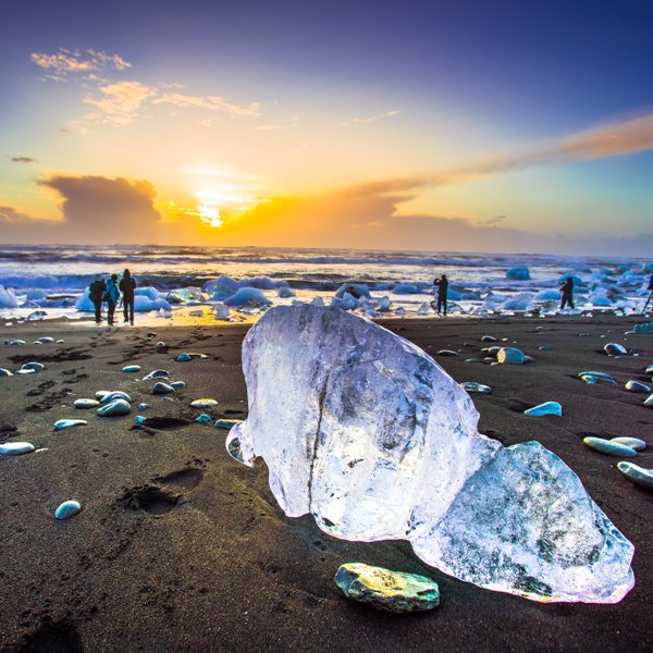 Ein Eisblock liegt bei traumhaftem Wetter am Strand