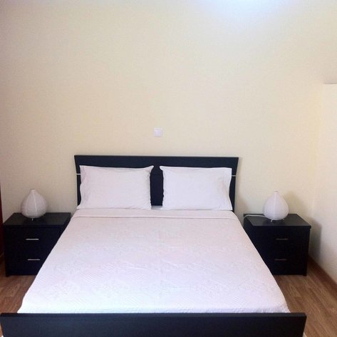 Ein gemütliches Schlafzimmer mit einem großen Bett, weißen Kissen und Nachttischen auf beiden Seiten.