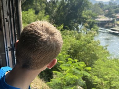 Junge blickt aus Fenster bei Zugfahrt mit Death Train - Thailand mit Kindern